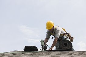 一位戴着防护头盔的建筑工人正在修理屋顶。