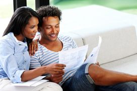 Young couple reading financial and tax paperwork at home.