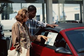 一个男人和一个女人在看一辆车的价格细节。