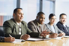 一群不同的商务人士坐在一张代表公司文化的桌子旁。